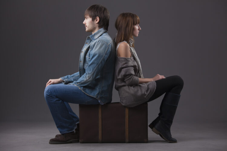 conflict in relationship - man and woman sitting on suitcase back on back
