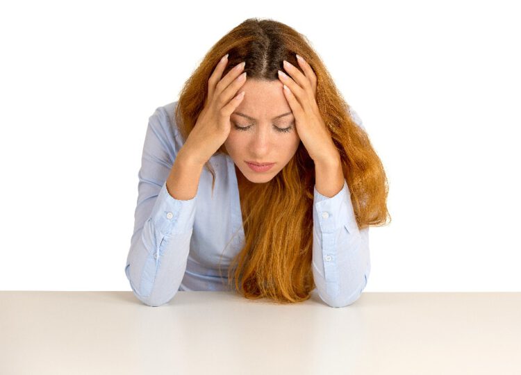 Desperate young business woman leaning on a desk looking down isolated on white  background. Negative human emotions face expression feelings life perception