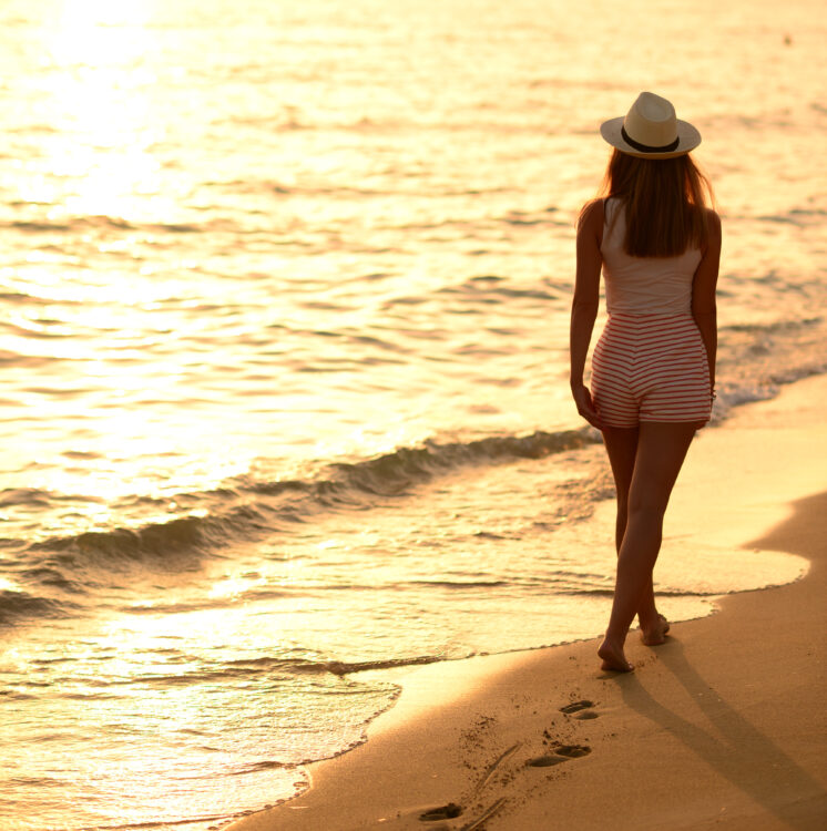 Beach travel - woman walking on sand beach leaving footprints in the sand
