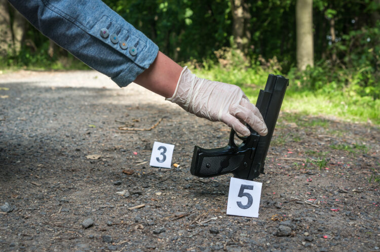 Investigator collects evidence (pistol) - crime scene investigation
