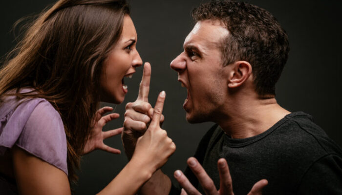Angry young couple shouting face to face.